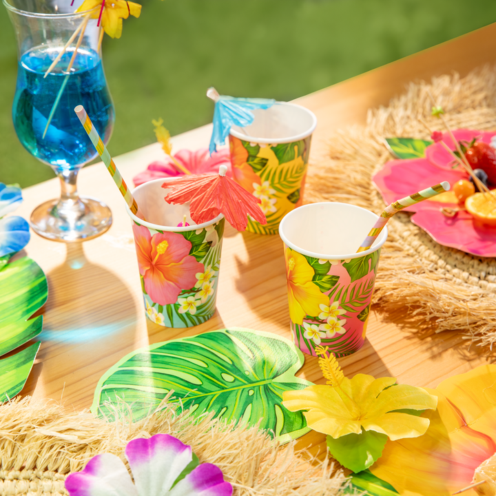 kubki papierowe aloha z motywem tropikalnych kwiatów w kolorze żółtym, różowym i pomarańczowym, parasolki koktajlowe, napoje, drinki, koktajle, serwetki w kształcie liści, słomki papierowe, tropikalne kwiaty