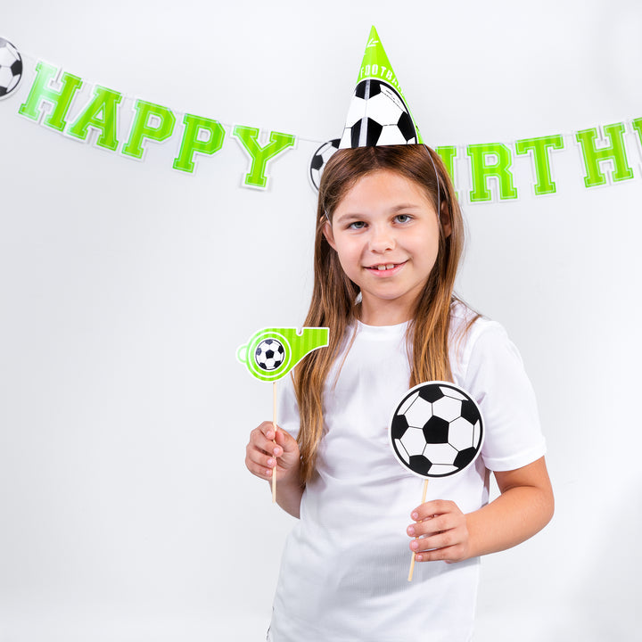 Uśmiechnięta dziewczynka z dwama rekwizytami fotograficznymi z kolekcji Football- gwizdkiem i piłką.