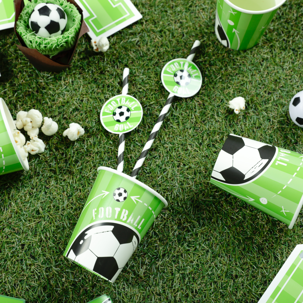 Na tle zielonej murawy leżą kubeczki i słomki z kolekcji Football.