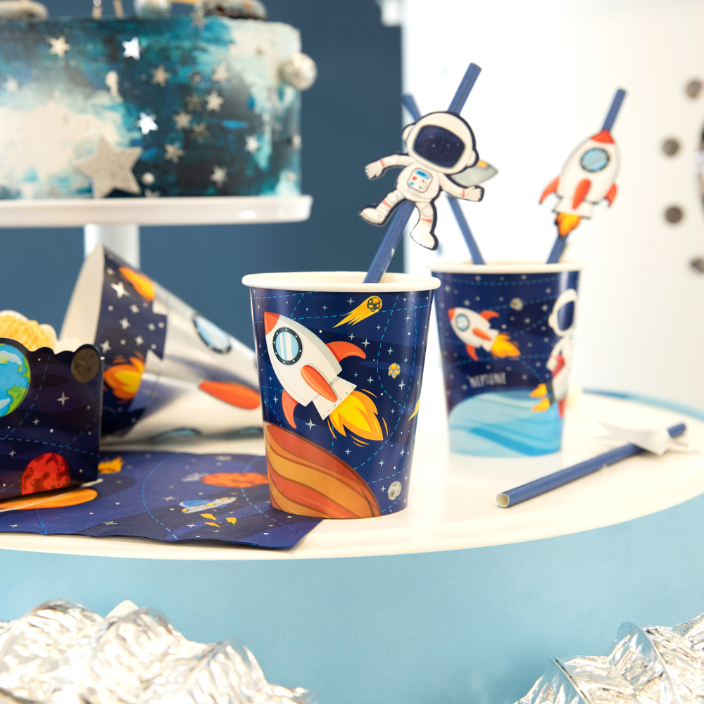 Zdjęcie przedstawia kubki i słomki z kolekcji Kosmos na tle tortu z gwiazdkami.