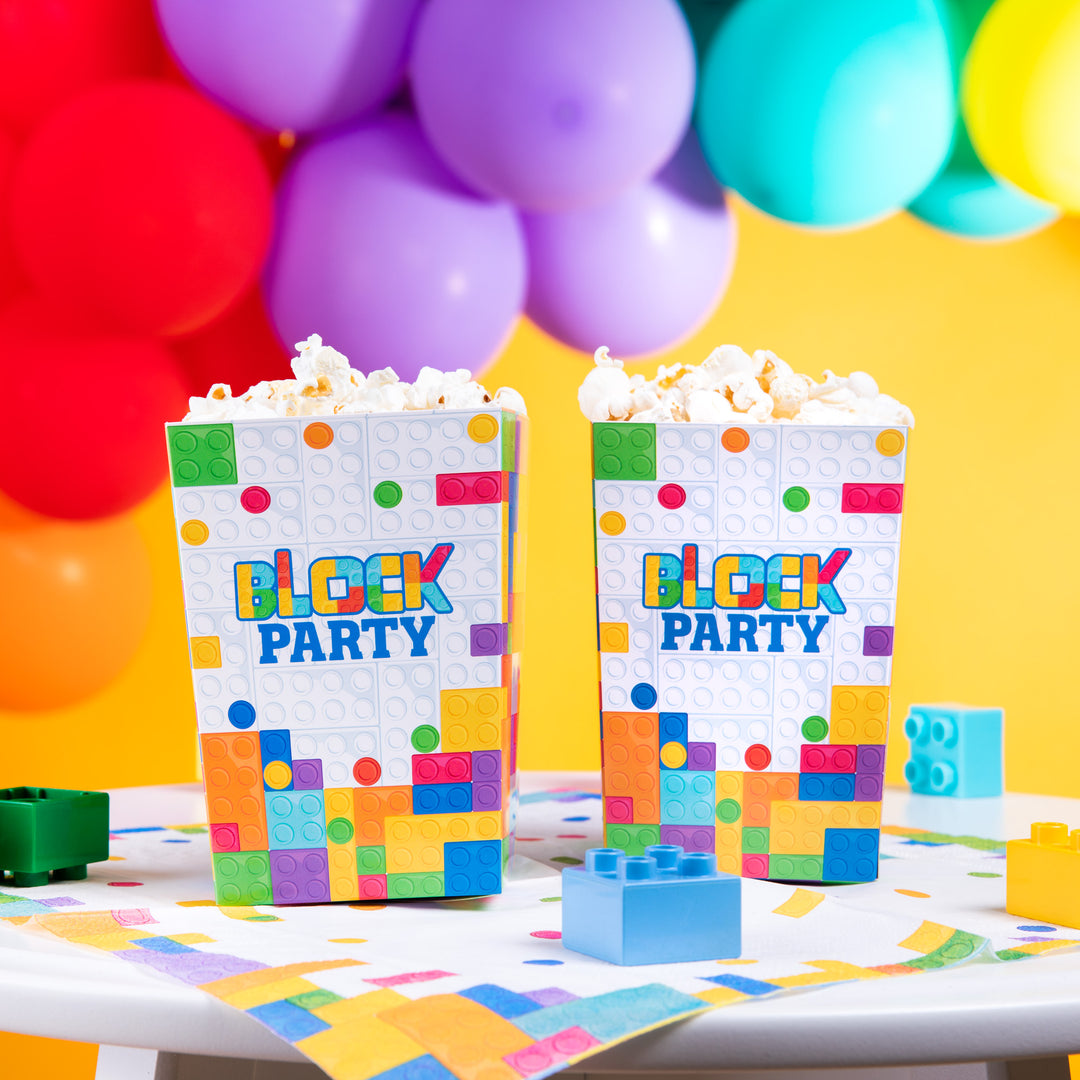 Dwa pudełka na popcorn stojące na stole, na serwetce z kolekcji Klocki.