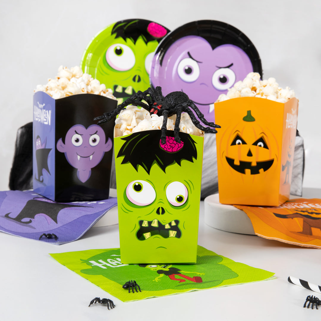 Pudełka na popcorn zombie, dynia i wampir z serwetkami, talerzykami i pająkami.