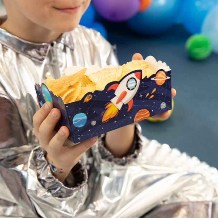 Chłopiec w kombinezonie astronauty trzyma pudełko z kolekcji Kosmos wypełnione chipsami