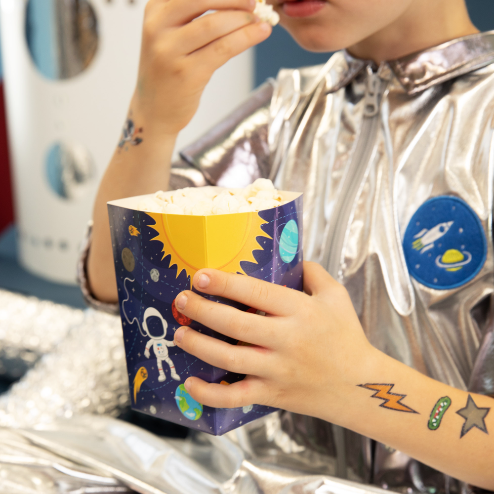 Dziecko jedzące popcorn na rączce ma trzy tatuaże z kolekcji Kosmos
