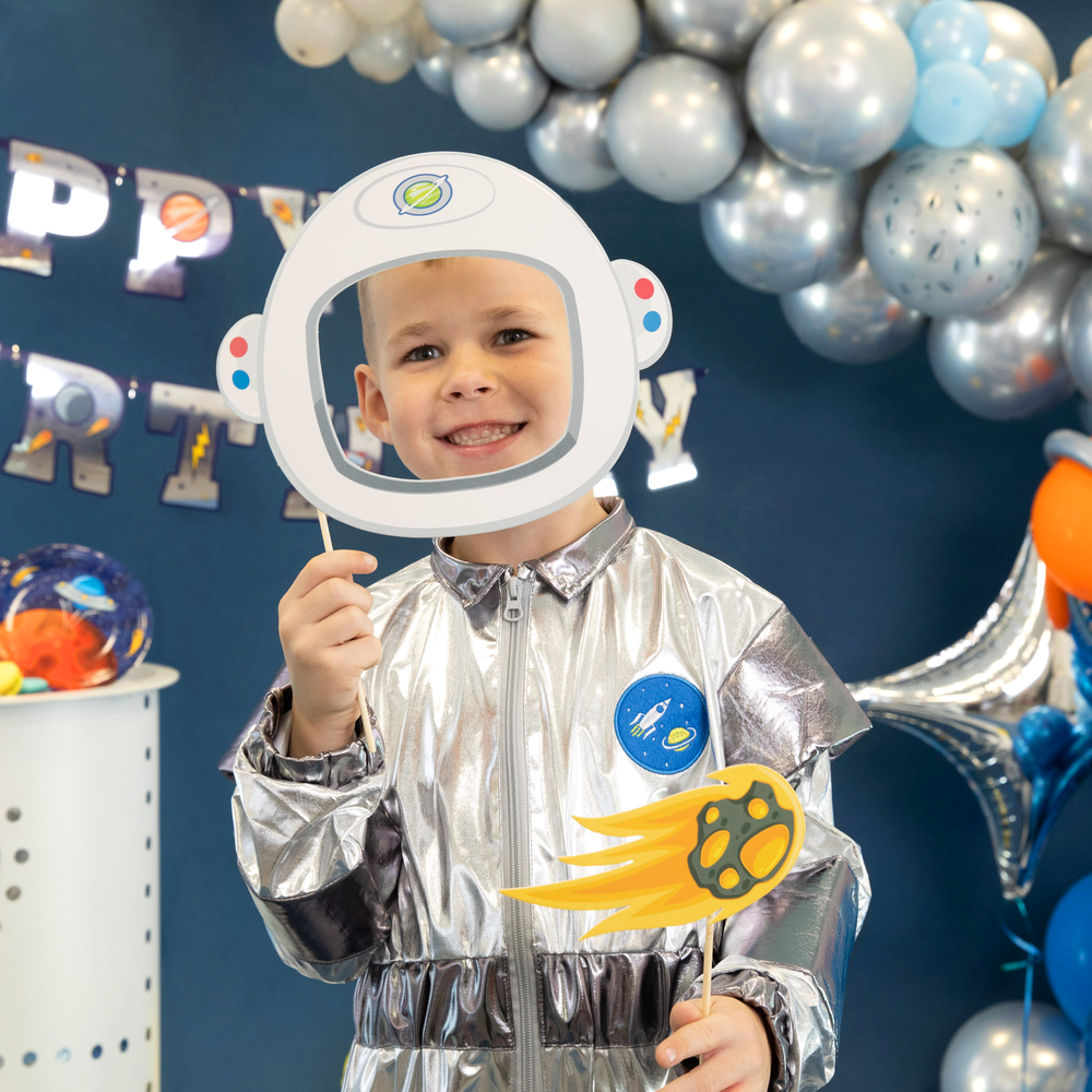 Chłopiec w kombinezonie astronauty pozuje do zdjęcia z chełmem astronauty i płonącym meteorytem