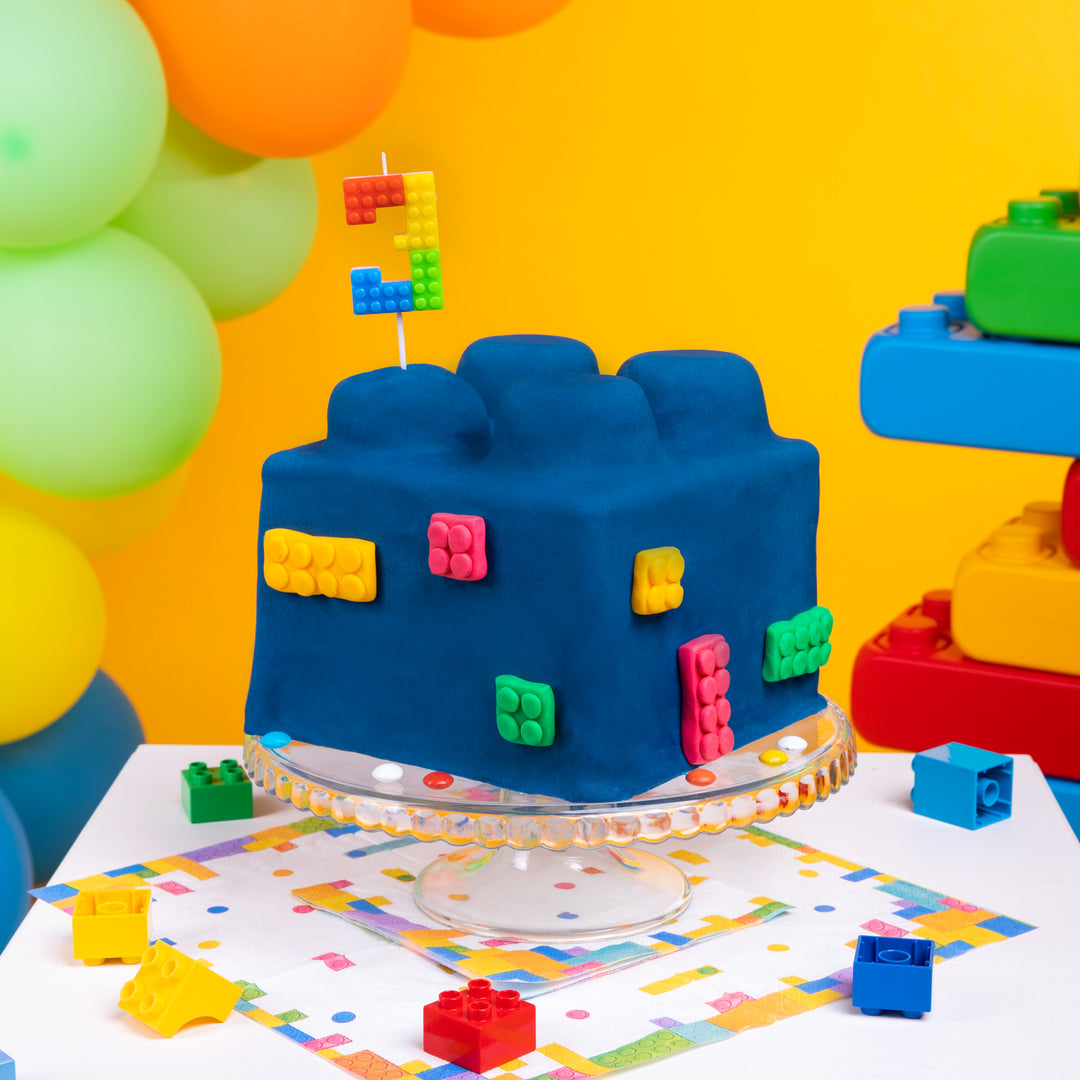 Niebieski tort wyglądający jak wielki klocek lego ze świeczką, cyfra 3, z kolekcji Klocki.