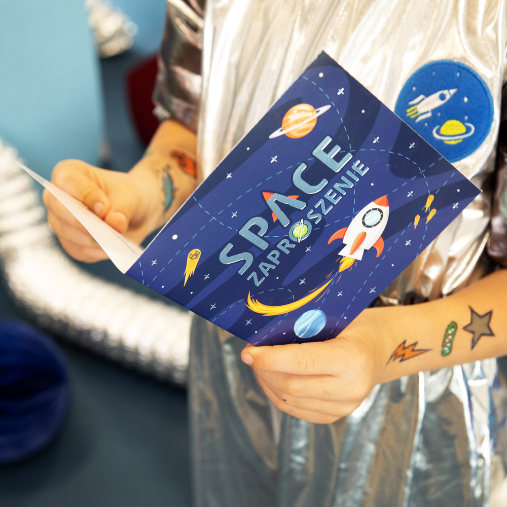 Dziecko trzyma w rękach zaproszenie na imprezę dziecięcą z kolekcji Kosmos